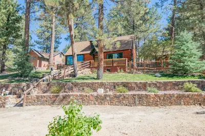 a log cabin in the woods with a stone wall at Big Bear Retreat - A charming mountain cabin with easy access to Big Bear's attractions! in Big Bear Lake