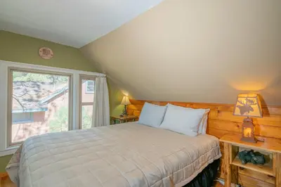 a bedroom with a bed and a large window at Big Bear Retreat - A charming mountain cabin with easy access to Big Bear's attractions! in Big Bear Lake
