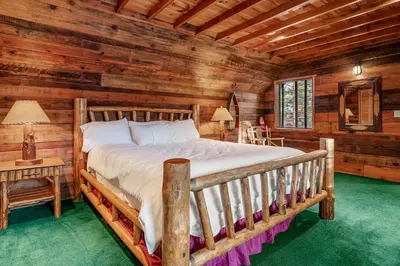 a bedroom with a bed in a log cabin at Blue Lagoon - Classic Lakefront Cabin with Pool Table! in Big Bear Lake