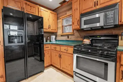 a kitchen with wooden cabinets and black appliances at Blue Lagoon - Classic Lakefront Cabin with Pool Table! in Big Bear Lake