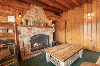 a living room with a stone fireplace in a cabin at Blue Lagoon - Classic Lakefront Cabin with Pool Table! in Big Bear Lake
