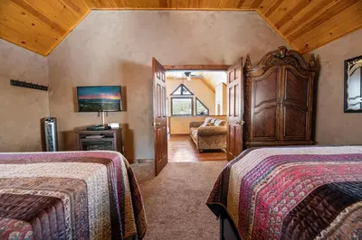 a bedroom with two beds and a chair in a room at Boulder Bay Park Lakefront - Across the street from the lake and Boulder Bay Park! Hot tub! in Big Bear Lake