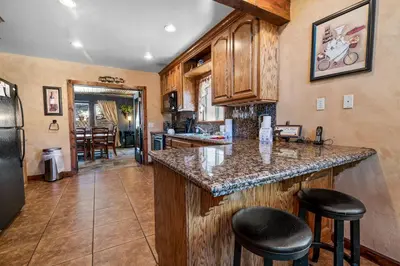 a kitchen with a counter with stools and a refrigerator at Boulder Bay Park Lakefront - Across the street from the lake and Boulder Bay Park! Hot tub! in Big Bear Lake