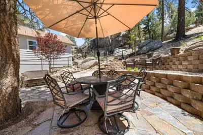 a table and chairs with an umbrella on a patio at Boulder Bay Park Lakefront - Across the street from the lake and Boulder Bay Park! Hot tub! in Big Bear Lake