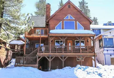 a large wooden house with a deck in the snow at Boulder Bay Park Lakefront - Across the street from the lake and Boulder Bay Park! Hot tub! in Big Bear Lake
