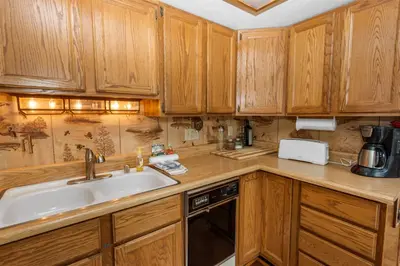 a kitchen with wooden cabinets and a sink at Boulder Pines - Walk to lake and Boulder Bay park at those cozy location! in Big Bear Lake