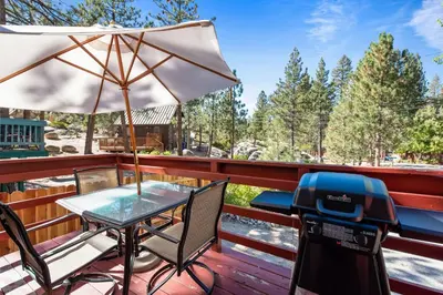 a table and chairs on a deck with an umbrella at Boulder Pines - Walk to lake and Boulder Bay park at those cozy location! in Big Bear Lake