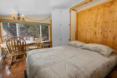 a bedroom with a bed and a table and a window at Boulder Pines - Walk to lake and Boulder Bay park at those cozy location! in Big Bear Lake