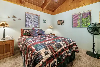 a bedroom with a bed and two windows at Catalina Retreat -Cozy mountain home in a tree filled neighborhood, plenty of games and a hot tub! in Big Bear Lake