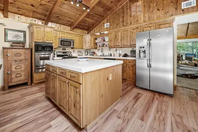 a kitchen with wooden cabinets and a stainless steel refrigerator at Catalina Retreat -Cozy mountain home in a tree filled neighborhood, plenty of games and a hot tub! in Big Bear Lake