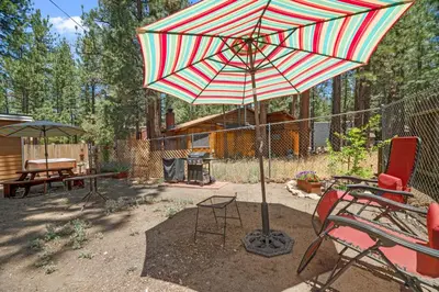 a patio with a red and white umbrella and chairs at Catalina Retreat -Cozy mountain home in a tree filled neighborhood, plenty of games and a hot tub! in Big Bear Lake