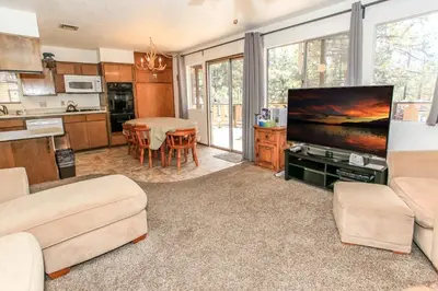 a living room with a flat screen tv and a kitchen at Chalet Georgia - Spacious and cozy home, conveniently close to the heart of Big Bear! in Big Bear Lake