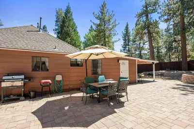 a patio with a table and chairs and an umbrella at Chipmunk House - Magical Boulder Bay cottage within a picturesque setting! in Big Bear Lake
