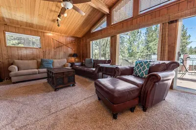 a living room with leather furniture and a large window at Cub Run Cabin - Spacious home close to the lake with Hot tub! in Big Bear Lake