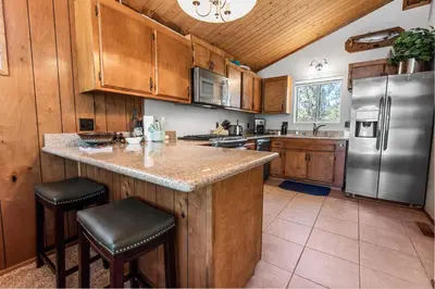 a kitchen with wooden cabinets and a stainless steel refrigerator at Cub Run Cabin - Spacious home close to the lake with Hot tub! in Big Bear Lake