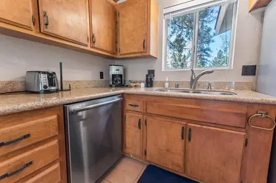 a kitchen with wooden cabinets and a sink and a window at Cub Run Cabin - Spacious home close to the lake with Hot tub! in Big Bear Lake