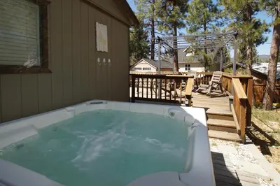 a hot tub on a patio with a deck at Dream Street Escape -Private Hot Tub, near the Village and Lake! in Big Bear Lake