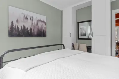 a bedroom with a white bed with a picture on the wall at Enchanted Hideaway - Newly remodeled with Hot Tub and Lake Views! in Fawnskin