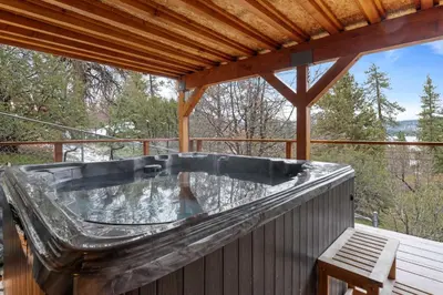 a hot tub on the deck of a cabin at Enchanted Hideaway - Newly remodeled with Hot Tub and Lake Views! in Fawnskin