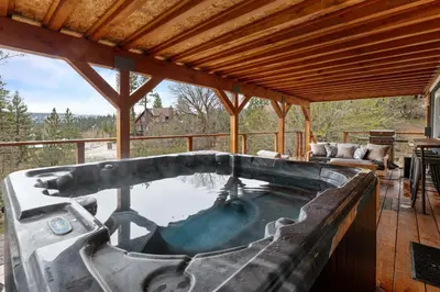 a hot tub on the deck of a house at Enchanted Hideaway - Newly remodeled with Hot Tub and Lake Views! in Fawnskin