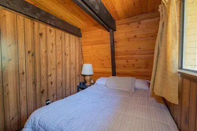 a bedroom with a bed in a wooden cabin at Fanciful Winter's Lake - Mix of old-world charm and modern-day gambrel style cabin! in Big Bear Lake