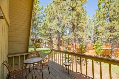 a porch with two chairs and a table and chairs at Fanciful Winter's Lake - Mix of old-world charm and modern-day gambrel style cabin! in Big Bear Lake