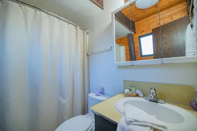 a bathroom with a sink and a toilet and a mirror at Fanciful Winter's Lake - Mix of old-world charm and modern-day gambrel style cabin! in Big Bear Lake