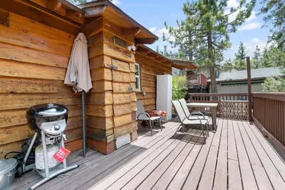 a wooden deck with an umbrella and a table and chairs at Finch Nest - Beautiful cabin in a convenient location! in Big Bear Lake