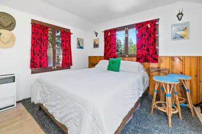 a bedroom with a bed and two windows with red curtains at Finns Fish Camp - Walking distance to Lake and Village! Back patio with barbecue, fully fenced yard! in Big Bear Lake