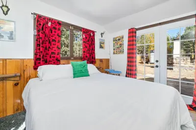 a bedroom with a white bed and red curtains at Finns Fish Camp - Walking distance to Lake and Village! Back patio with barbecue, fully fenced yard! in Big Bear Lake