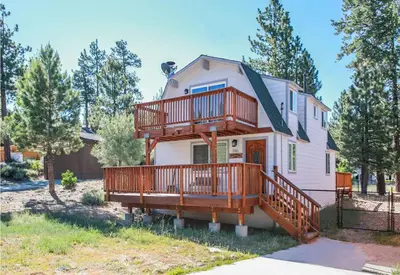 a house with a large deck on the side of it at Five Pines - Beautifully remodeled gambrel cabin with Hot Tub and Fenced Yard! in Big Bear Lake