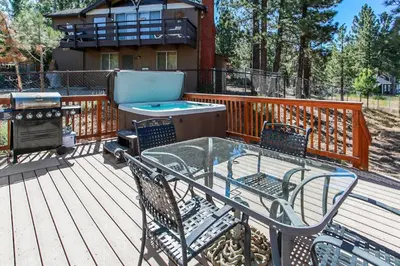 a deck with a table and chairs and a grill at Five Pines - Beautifully remodeled gambrel cabin with Hot Tub and Fenced Yard! in Big Bear Lake