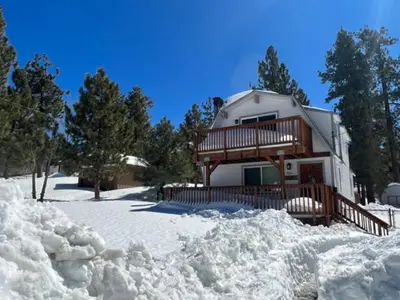 a house with a deck in the snow at Five Pines - Beautifully remodeled gambrel cabin with Hot Tub and Fenced Yard! in Big Bear Lake