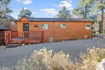 a log cabin with a porch and a driveway at Forest Edge Retreat - Cozy, log cabin with a wood burning fireplace! Pool Table, Foosball and Darts! in Big Bear City
