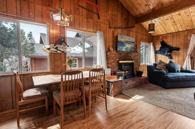 a living room with a table and chairs and a couch at Forest Edge Retreat - Cozy, log cabin with a wood burning fireplace! Pool Table, Foosball and Darts! in Big Bear City