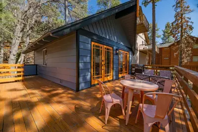 a tiny house with a table and chairs on a deck at Forest Escape - Situated on the quiet side of the lake, nicely decorated contemporary cabin! in Fawnskin
