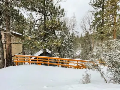 an orange fence in the snow next to a house at Forest Escape - Situated on the quiet side of the lake, nicely decorated contemporary cabin! in Fawnskin