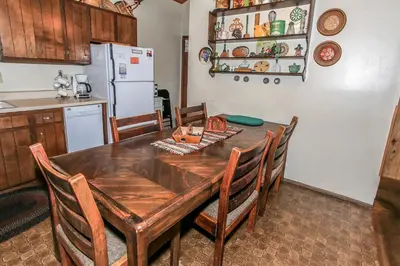 a kitchen with a wooden table with chairs and a refrigerator at Gallagher's West - Pine surrounded deck and barbecue! Bumper Pool and Wet bar! Darts! in Big Bear Lake