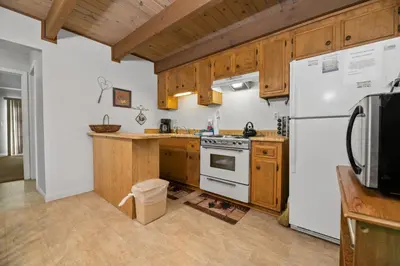 a kitchen with wooden cabinets and a white refrigerator at Glenview Getaway - Cozy farm house! Walking distance to the lake! in Big Bear Lake