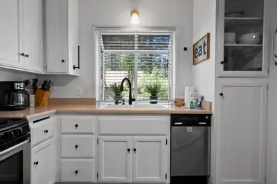 a kitchen with white cabinets and a sink and a window at Happy Hours - Modern Cabin with Game Room and Peek-a-Boo Lake Views! in Big Bear Lake