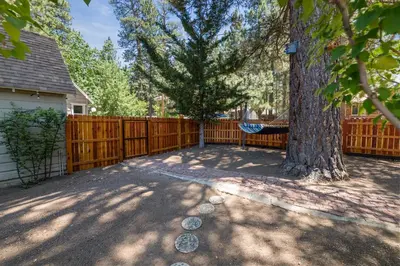 a yard with a tree and a hammock next to a fence at Happy Hours - Modern Cabin with Game Room and Peek-a-Boo Lake Views! in Big Bear Lake
