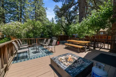 a deck with a fire pit and a table and chairs at Happy Hours - Modern Cabin with Game Room and Peek-a-Boo Lake Views! in Big Bear Lake