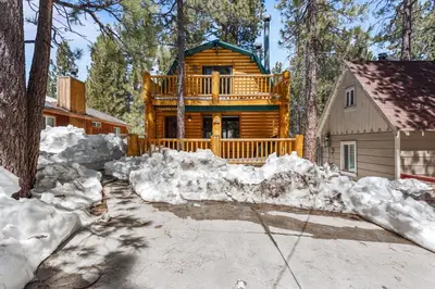 a log cabin in the woods with snow around it at Ivvy Bear Lodge - Charming log cabin with Hot tub! Short walk to Village! in Big Bear Lake