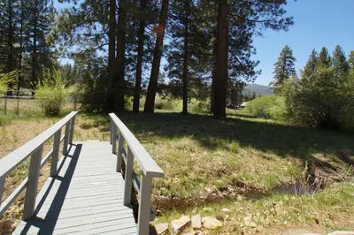 a wooden bridge over a field with trees at Jaybird Lodge - Large and spacious home near the Lake and Village! in Big Bear Lake