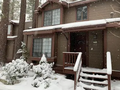 a house covered in snow in front of a house at Junipine Lakefront Condo - Walking distance to the lake! Less than 2 miles from the slopes! in Big Bear Lake