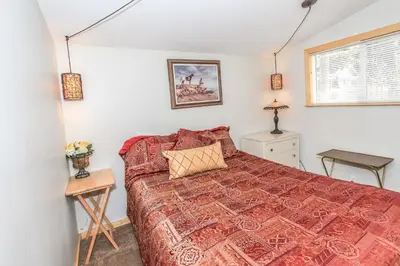 a bedroom with a bed with a red bedspread at Knotty Knight- Walking distance to the lake as well as the Village! in Big Bear Lake