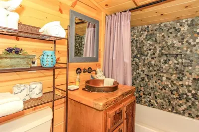 a bathroom in a log cabin with a sink and a tub at Knotty Knight- Walking distance to the lake as well as the Village! in Big Bear Lake