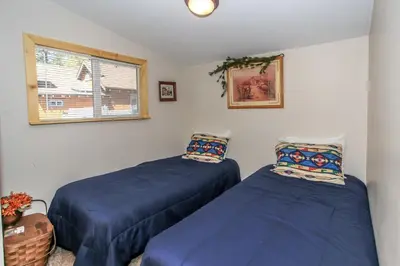 two blue beds in a room with a window at Knotty Knight- Walking distance to the lake as well as the Village! in Big Bear Lake