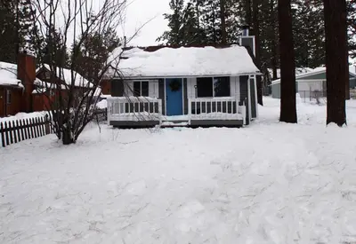 a small house with a blue door in the snow at Knotty Knight- Walking distance to the lake as well as the Village! in Big Bear Lake