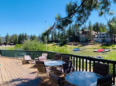 a patio with tables and chairs next to a river at Lakefront Viking Oasis - Beautiful Viking Estates condo complex on the lake! in Big Bear Lake